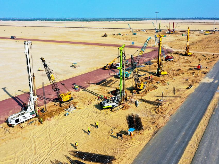 large construction site with rigs in remote area next to long stretch of road